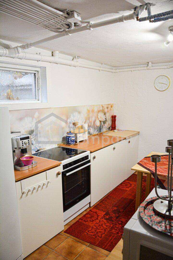 Kleine Küchenzeile im Keller mit Kochfeld, Backofen und Arbeitsplatte.