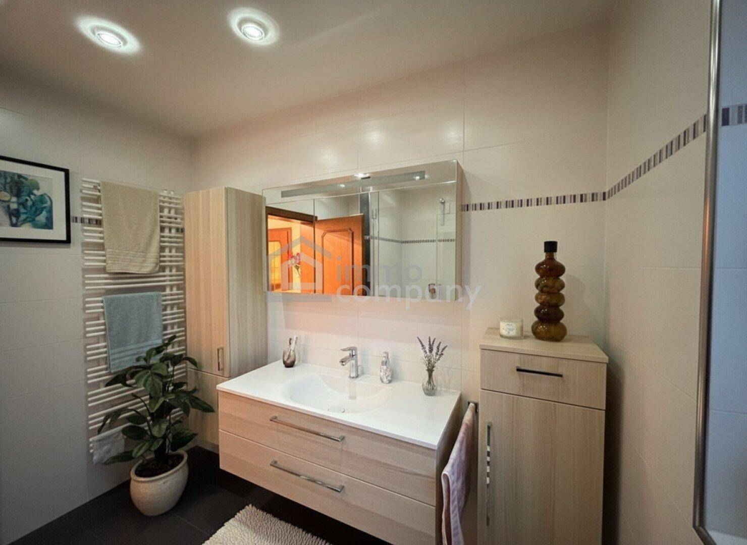 Modernes Badezimmer mit Waschtisch, Spiegelschrank und beheiztem Handtuchhalter.