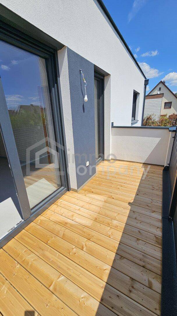 Moderner Balkon mit Holzdielenboden und dunkler Wand, ideal für entspannte Stunden im Freien.