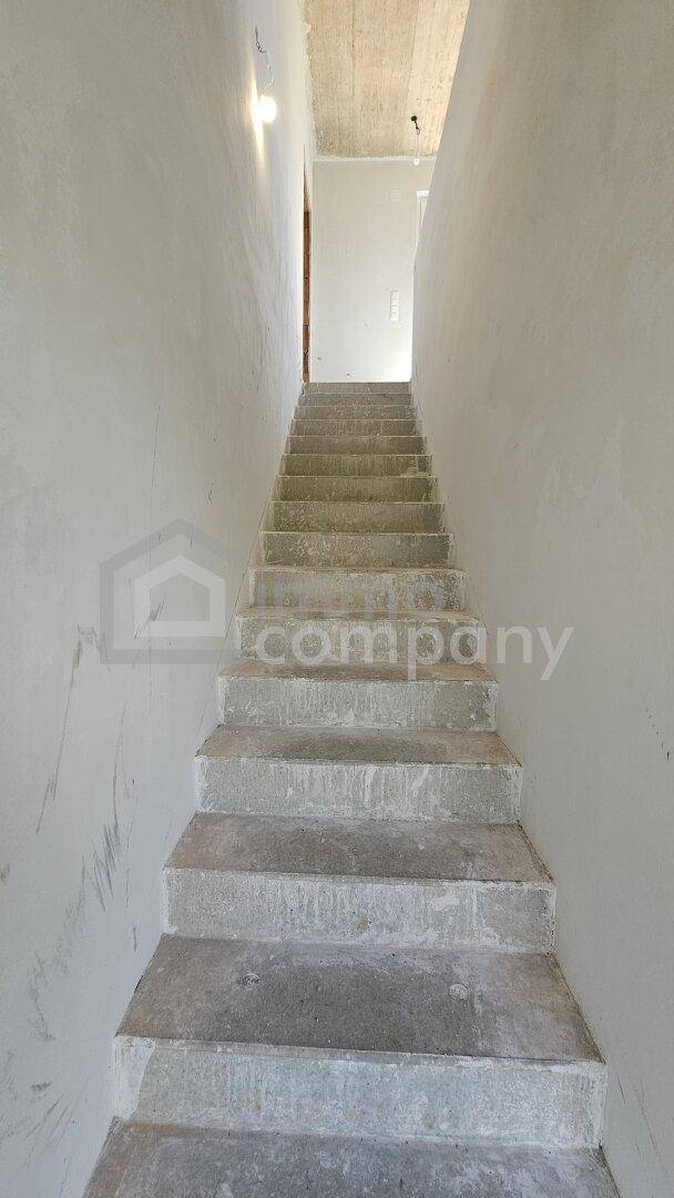 Treppenhaus im Rohbau mit Betonstufen und einfachen Wänden, bereit für den weiteren Ausbau.
