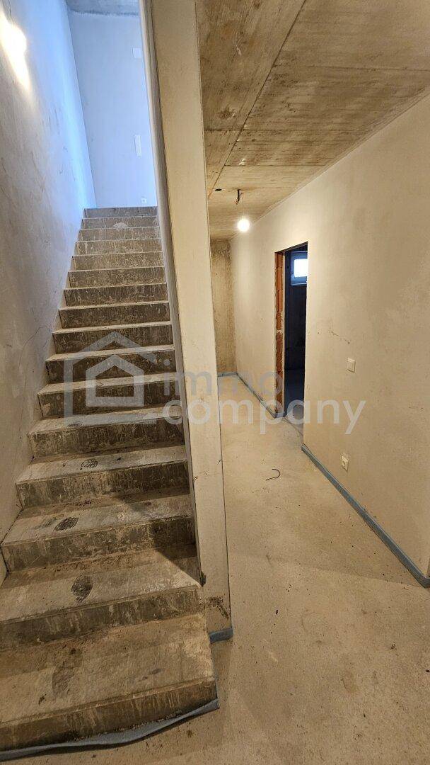 Flur und Treppenhaus im Rohbau mit Betonstufen und einfachen Wänden, bereit für den Ausbau.