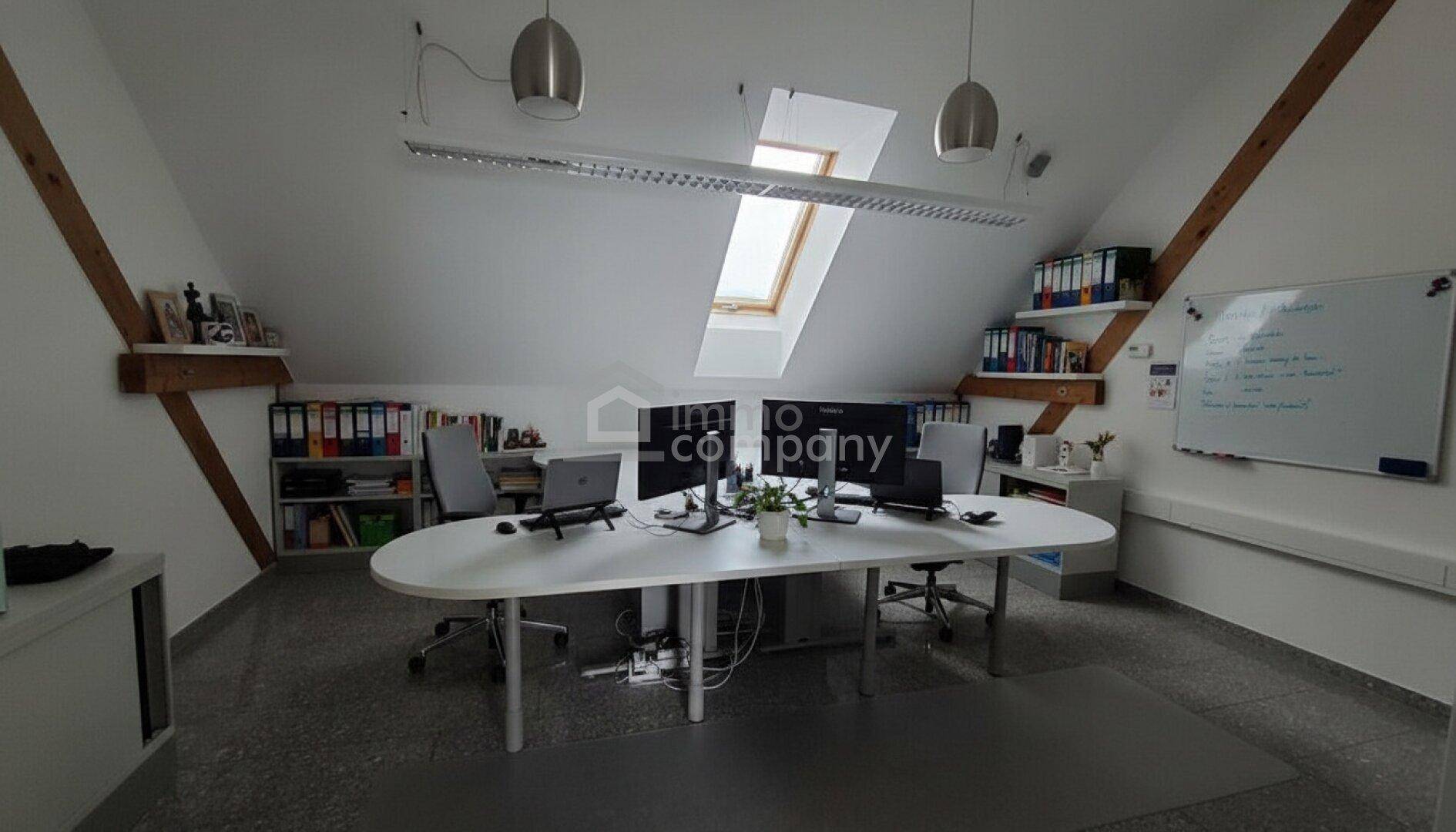 Funktionales Dachgeschossbüro mit mehreren Arbeitsplätzen, Dachfenstern und Regalen für Akten.
