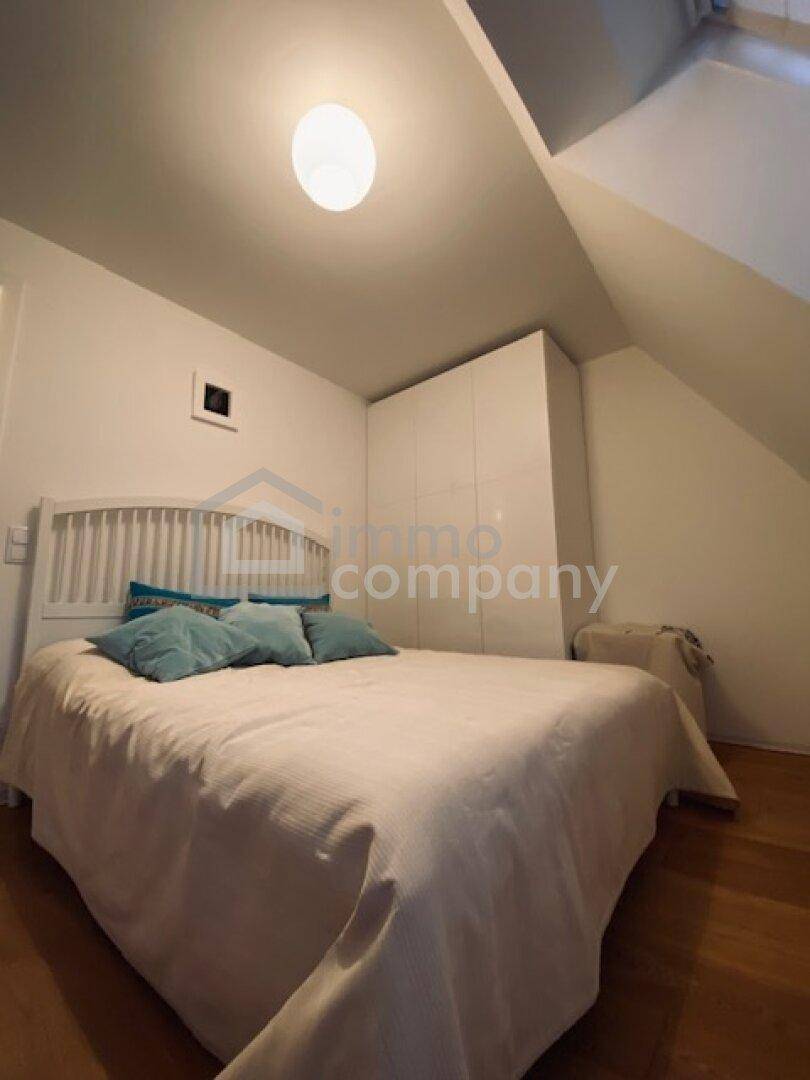 Helles Schlafzimmer mit Holzboden, weißem Kleiderschrank und schrägen Wänden im Dachgeschoss.