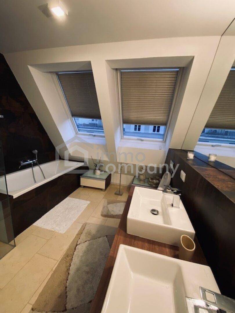 Modernes Badezimmer mit Doppelwaschbecken, Badewanne und Dachfenstern für natürliches Licht.