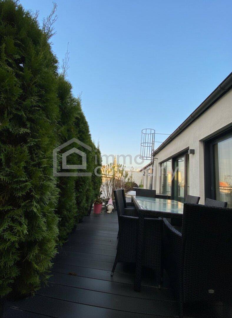 Geräumige Dachterrasse mit hoher Hecke, Outdoor-Sitzbereich und Holzboden für entspannte Stunden.