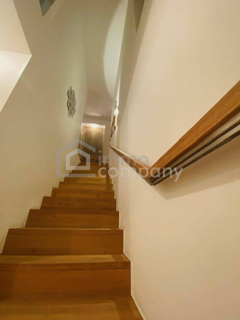 Elegante Holztreppe mit modernem Geländer führt zu den oberen Etagen des Hauses.
