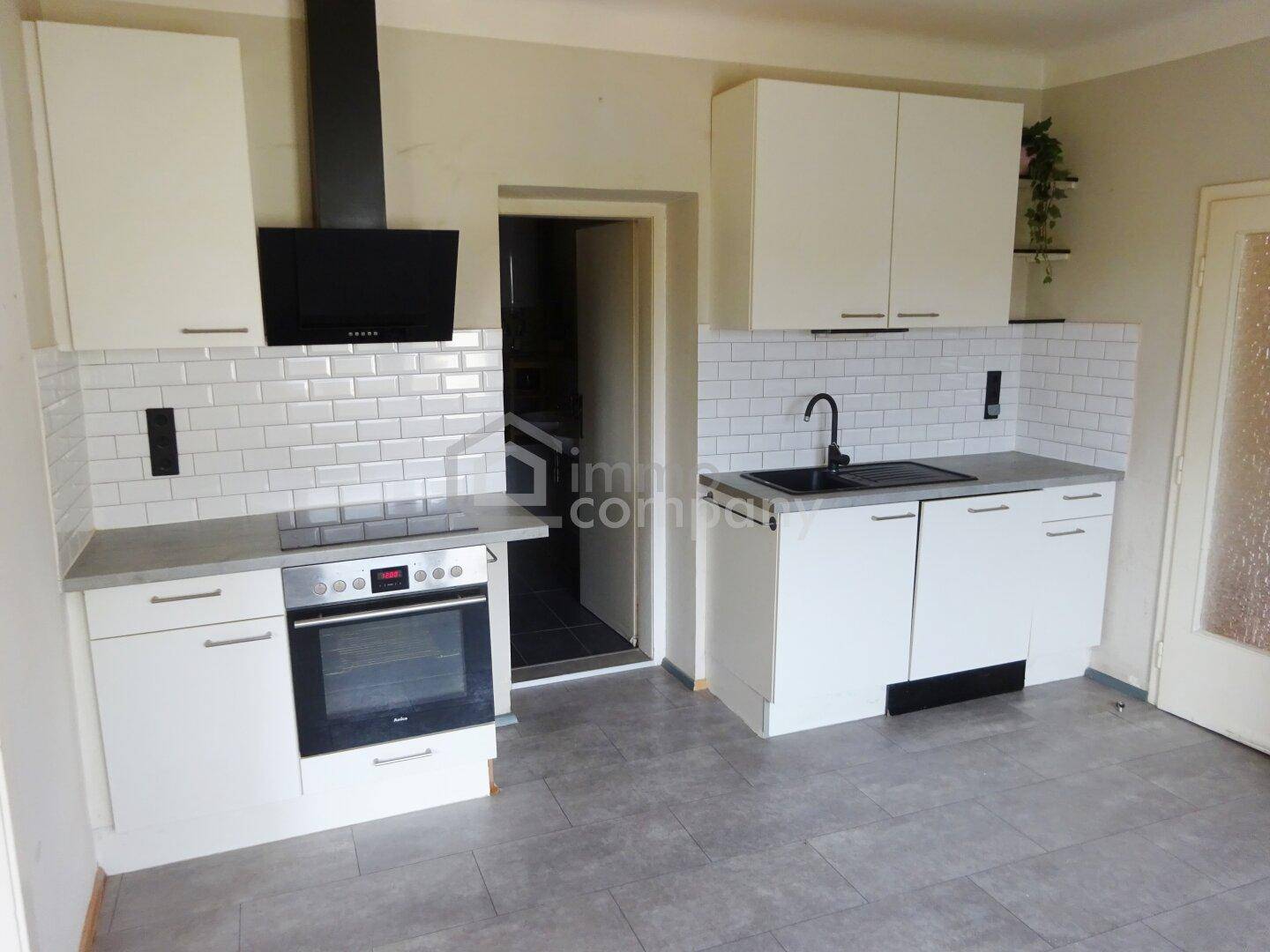 Moderne Einbauküche mit weißen Schränken, Induktionskochfeld und Dunstabzugshaube.