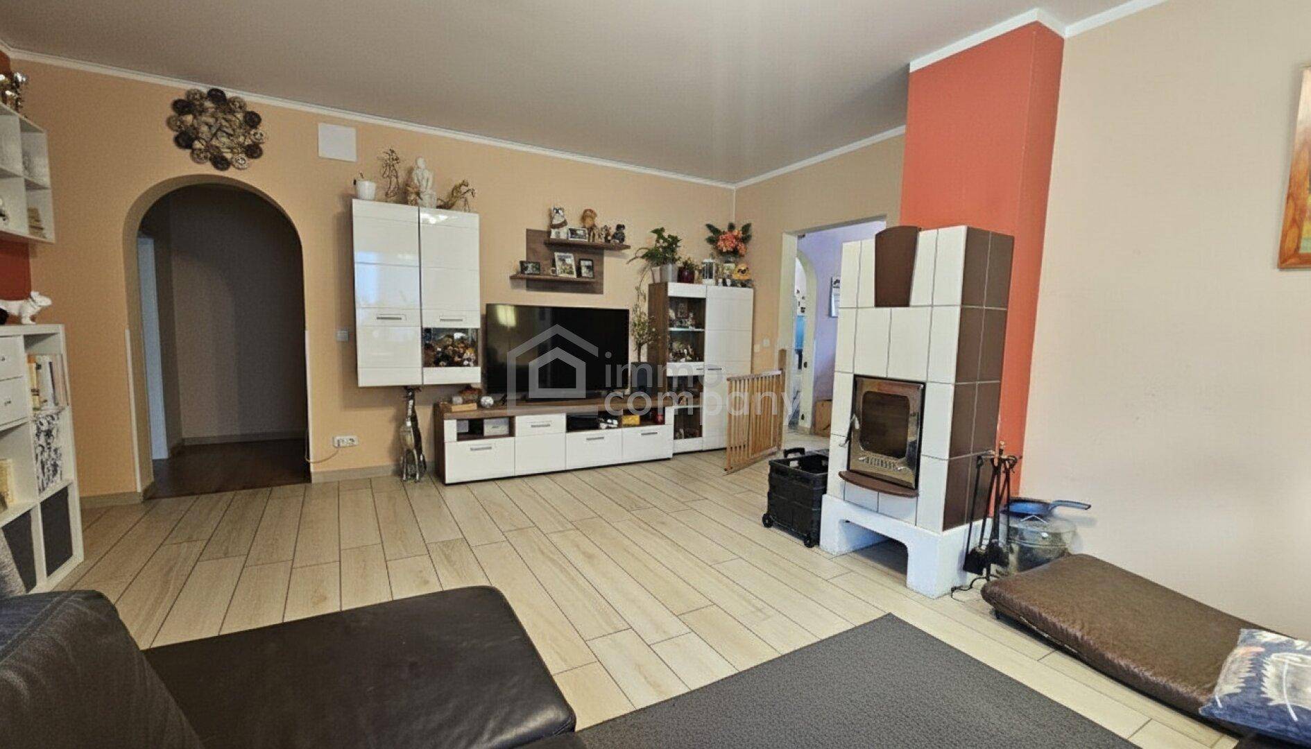 Geräumiges Wohnzimmer mit Kachelofen, Ledersofa und modernen Möbeln.