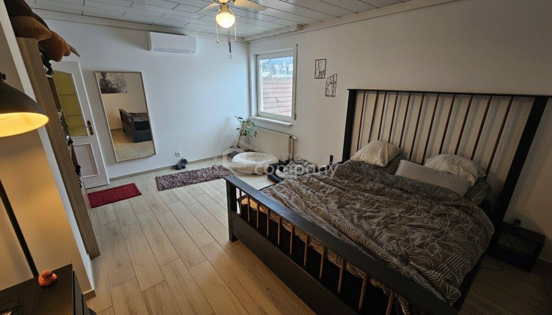 Helles Schlafzimmer mit Holzboden, großem Bett und Klimaanlage.