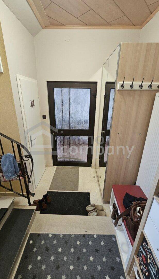 Eingangsbereich mit Garderobe, Spiegel und Treppe zum Obergeschoss.