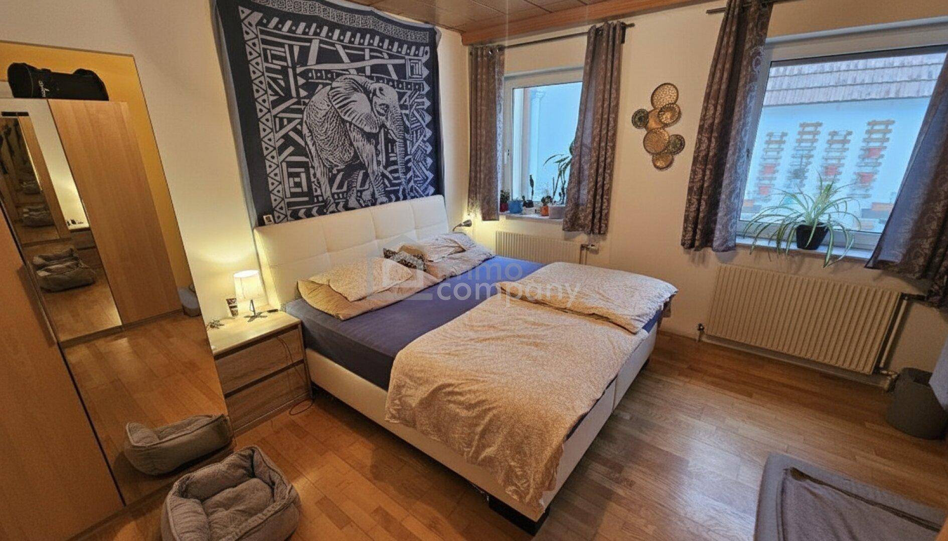 Gemütliches Schlafzimmer mit Doppelbett, Holzboden und dekorativem Wandteppich.