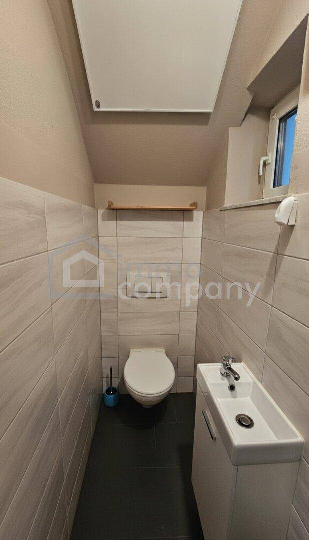 Kleines Gäste-WC mit modernem Waschbecken, Wand-WC und Fenster.