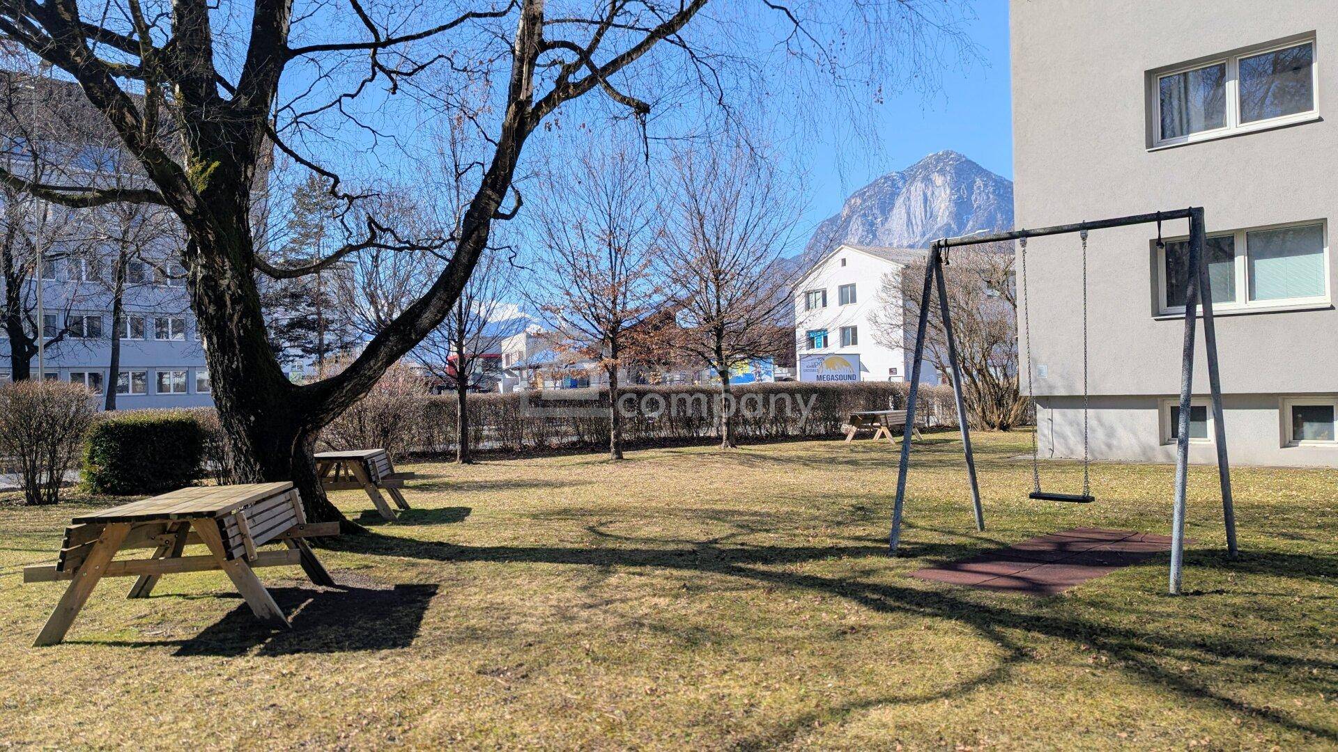 Gemeinschaftlicher Gartenbereich mit Schaukel, Picknicktischen und Blick auf die Berge.