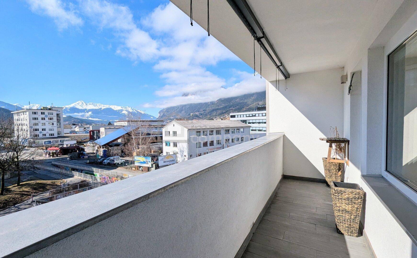 Sonnenverwöhnter Balkon mit weitem Blick auf die umliegende Berglandschaft und die Stadt.