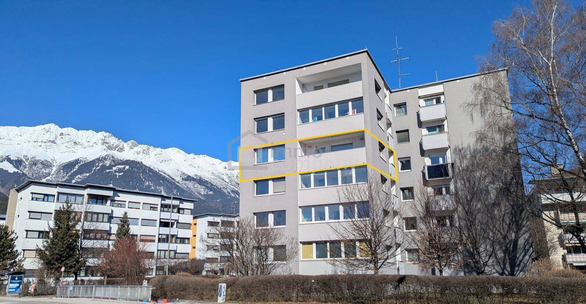 Mehrfamilienhaus in städtischer Umgebung mit Bergblick, die Wohnung ist markiert.