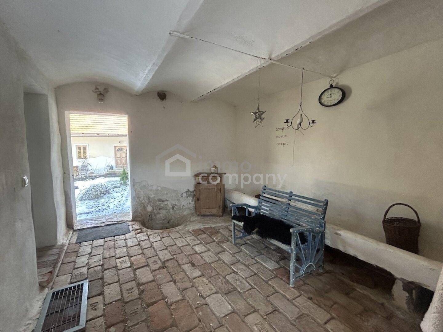 Rustikaler Eingangsbereich mit Ziegelboden und gewölbter Decke, führt nach draußen.