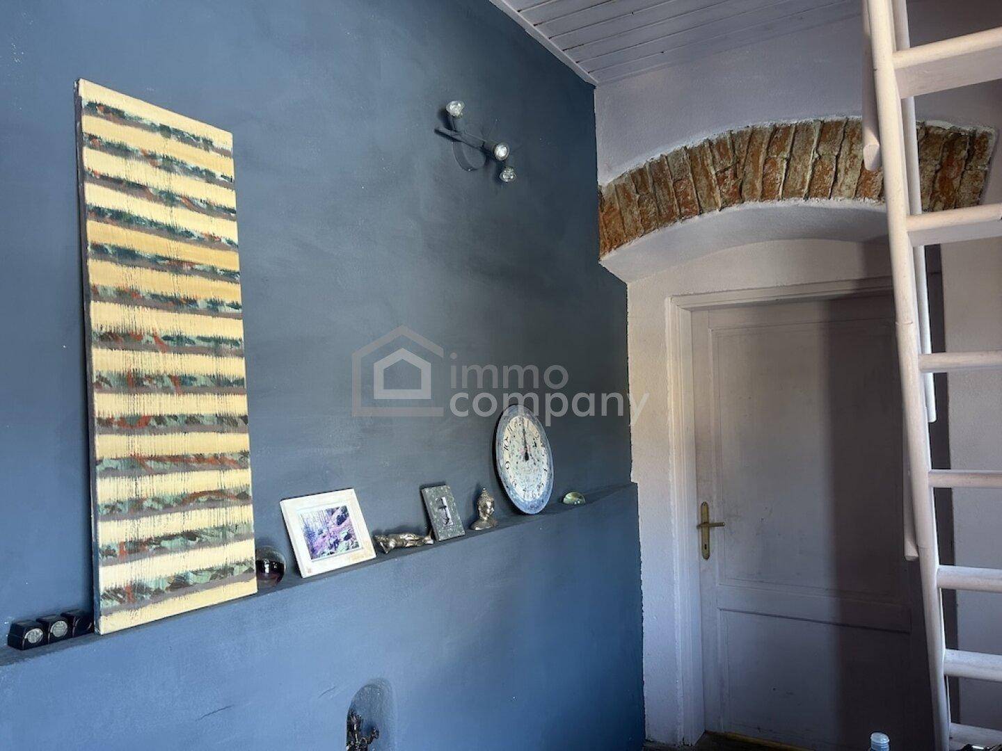 Flur mit blauer Wand, dekorativen Elementen und einem gemauerten Bogen über der Tür.