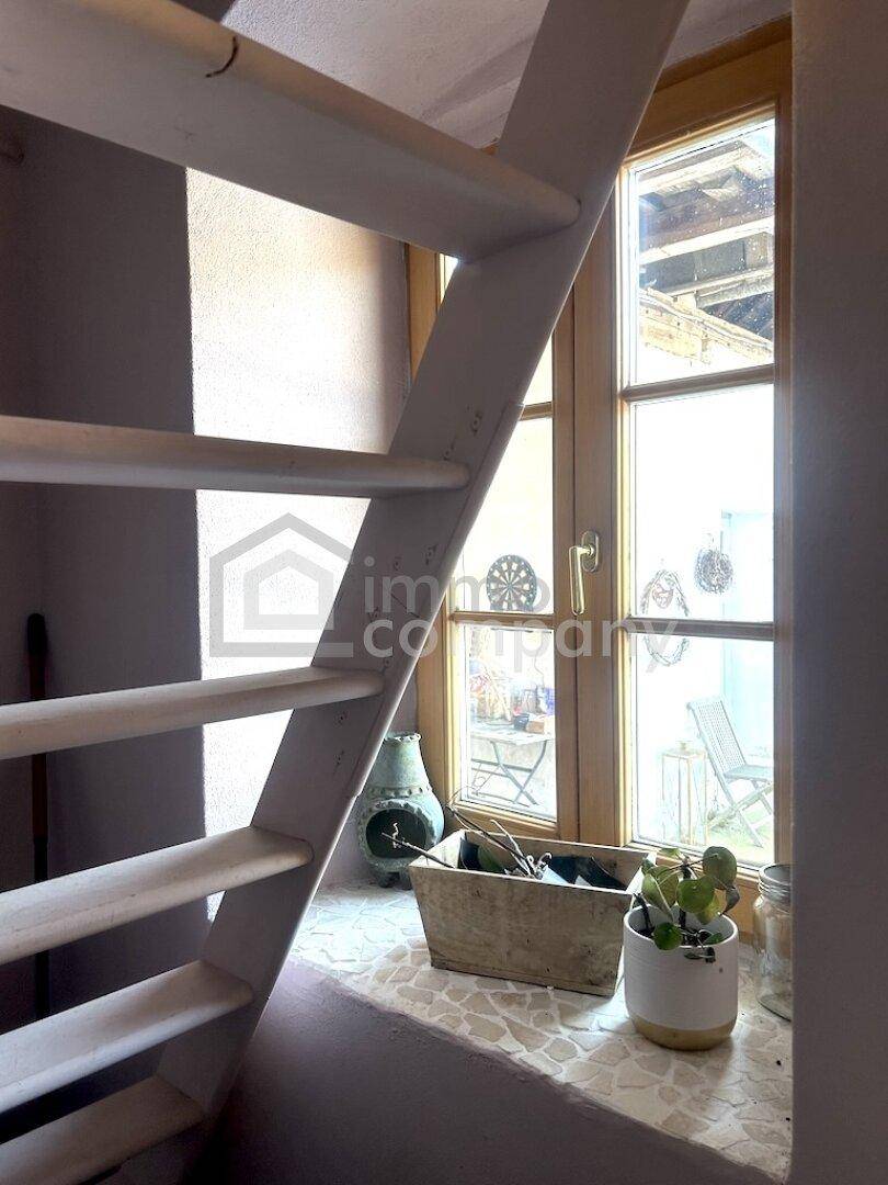 Helle Treppe neben einem Fenster mit Blick nach draußen und dekorativen Pflanzen.