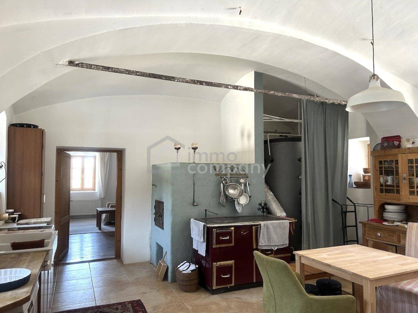 Geräumige Küche mit gewölbter Decke, traditionellem Ofen und Holztisch.