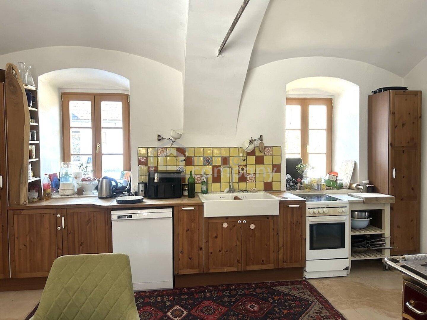 Rustikale Küche mit Holzeinbauten, Spülmaschine und farbigen Fliesen an der Wand.