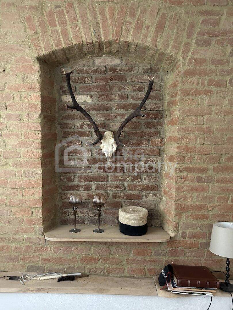 Dekorative Nische in einer Ziegelwand mit Hirschgeweih und Kerzenständern.