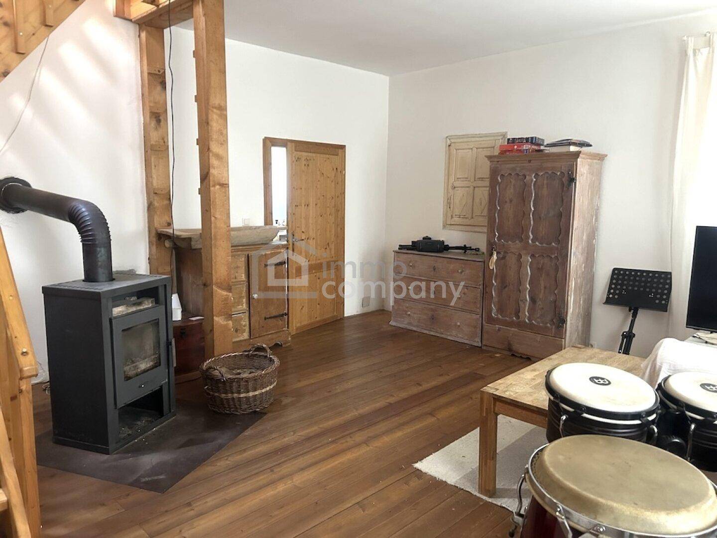 Geräumiges Wohnzimmer mit Holzboden, Kaminofen und rustikalen Holzmöbeln.
