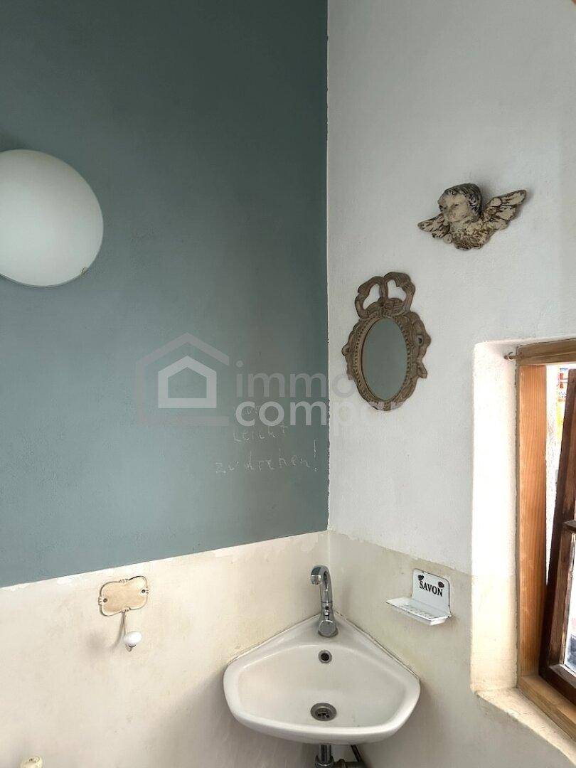 Kleines WC mit Eckwaschbecken, blauer Wand und dekorativen Elementen.