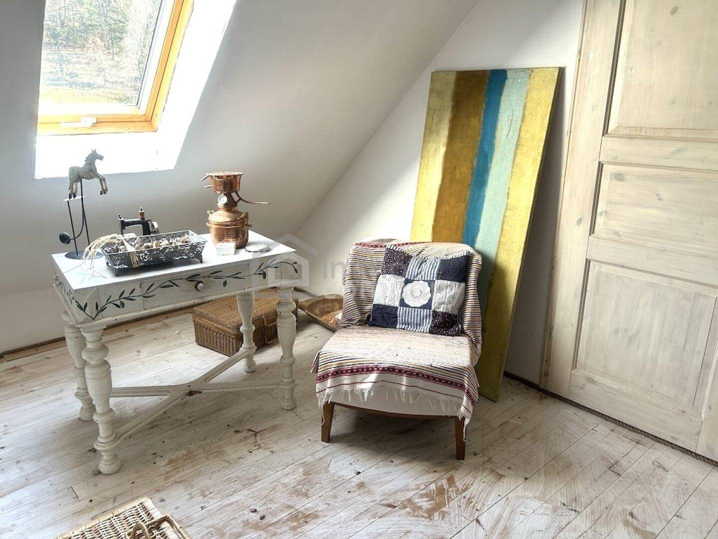 Gemütlicher Dachbodenraum mit schräger Decke, Dachfenster und rustikalen Möbeln.