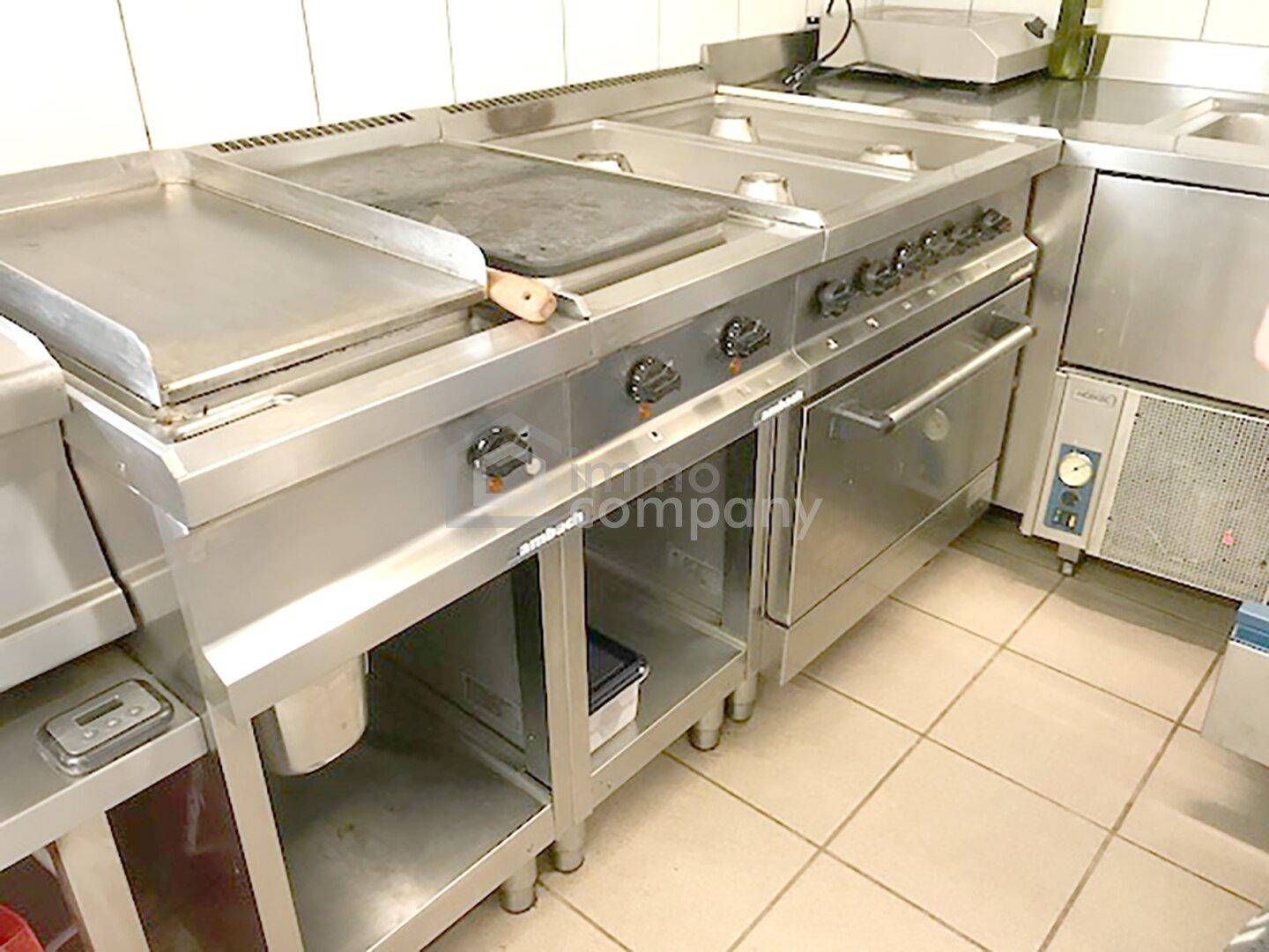 Professioneller Gasherd mit Grillplatte und Backofen in einer Großküche, bereit zum Kochen.