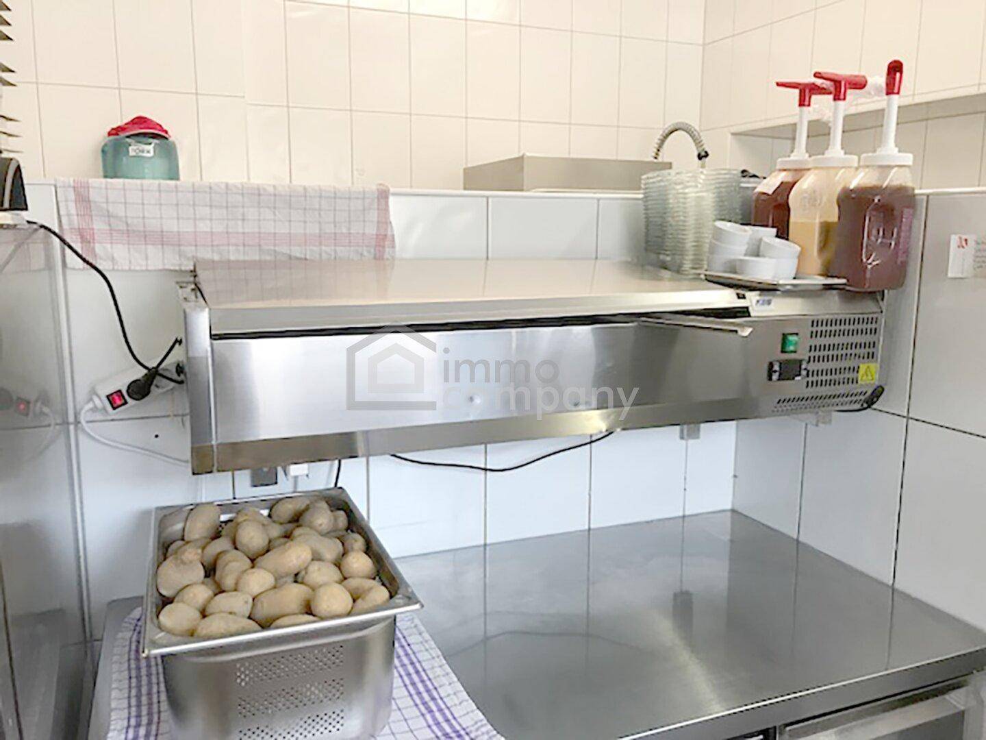 Vorbereitungsbereich in einer Großküche mit Edelstahlflächen und frischen Kartoffeln.