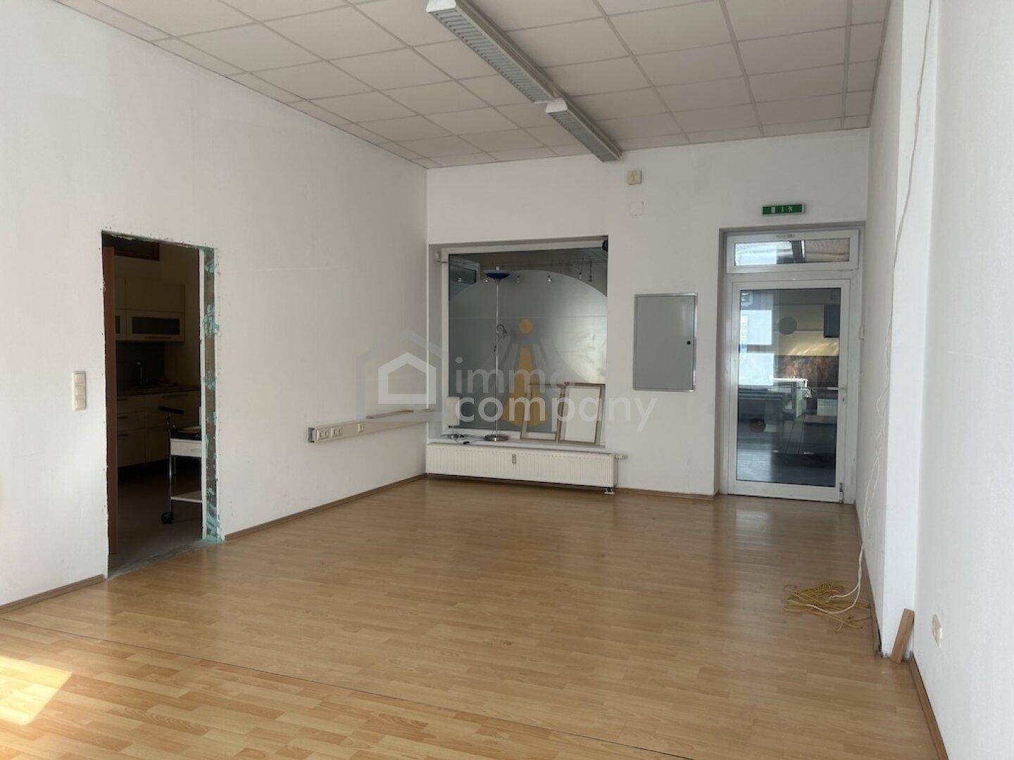 Großer, offener Geschäftsraum mit Holzfußboden und Schaufensterfront.