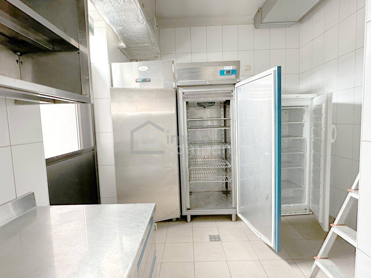 Kühlraum in einer Großküche mit offenen Kühlschränken und Regalen, bereit für Lebensmittel.
