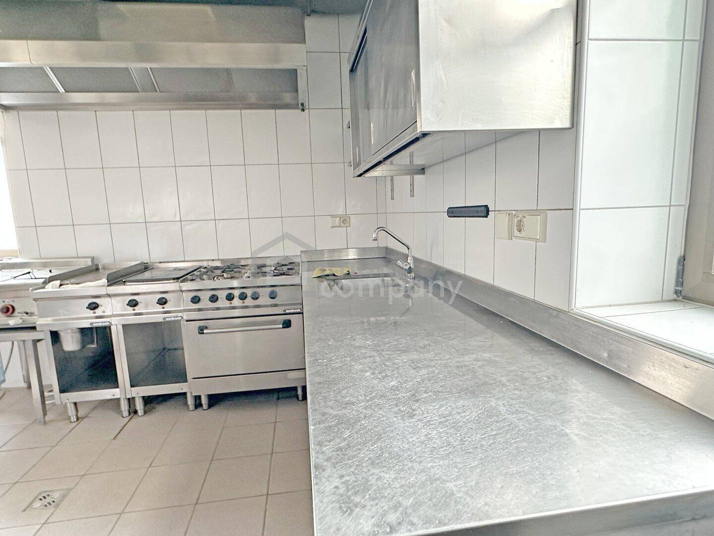 Professionelle Großküche mit Edelstahl-Arbeitsflächen und Gasherd, sauber und funktional.