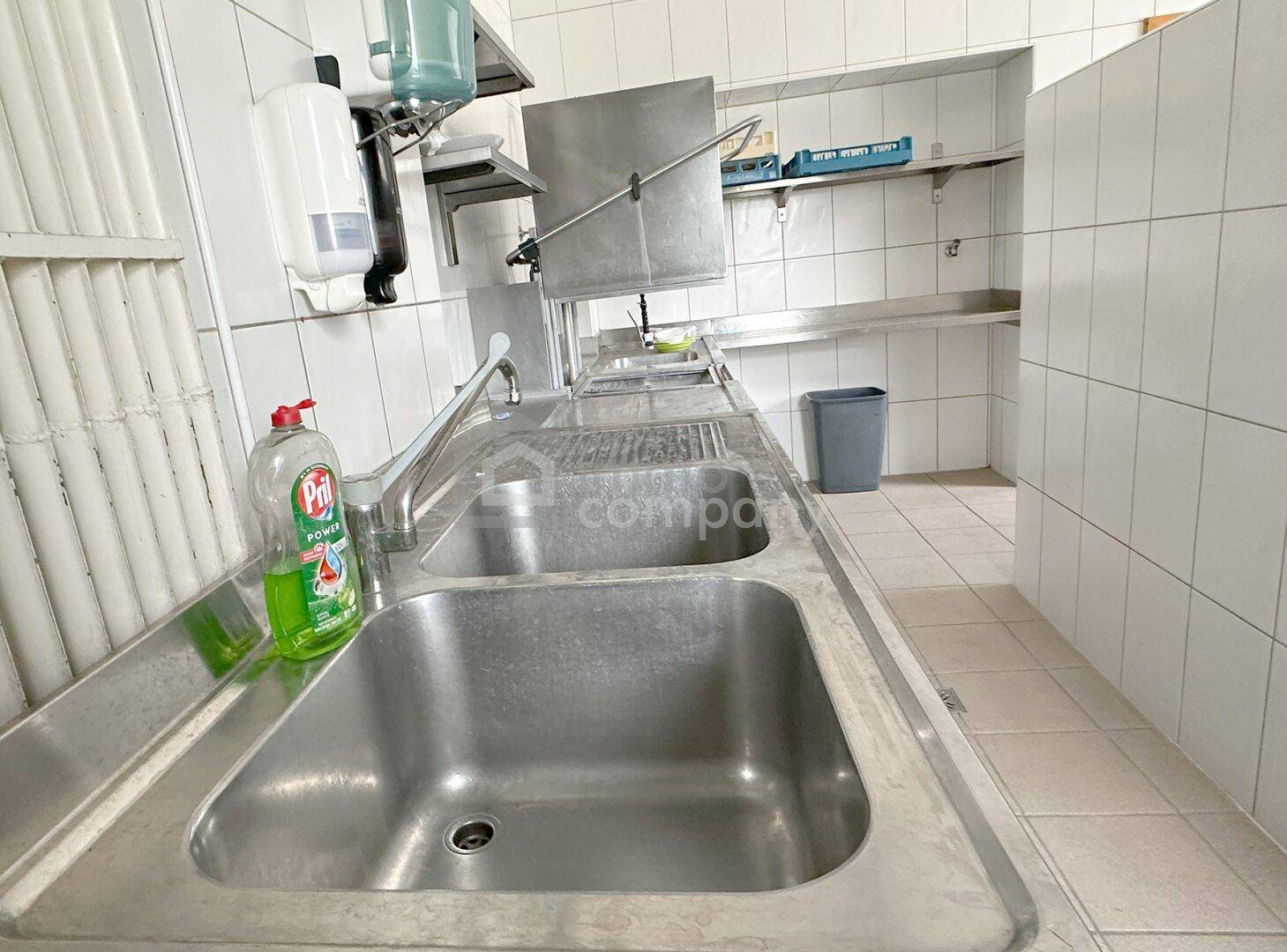 Spülbereich in einer Großküche mit Doppelwaschbecken aus Edelstahl und Ablageflächen.