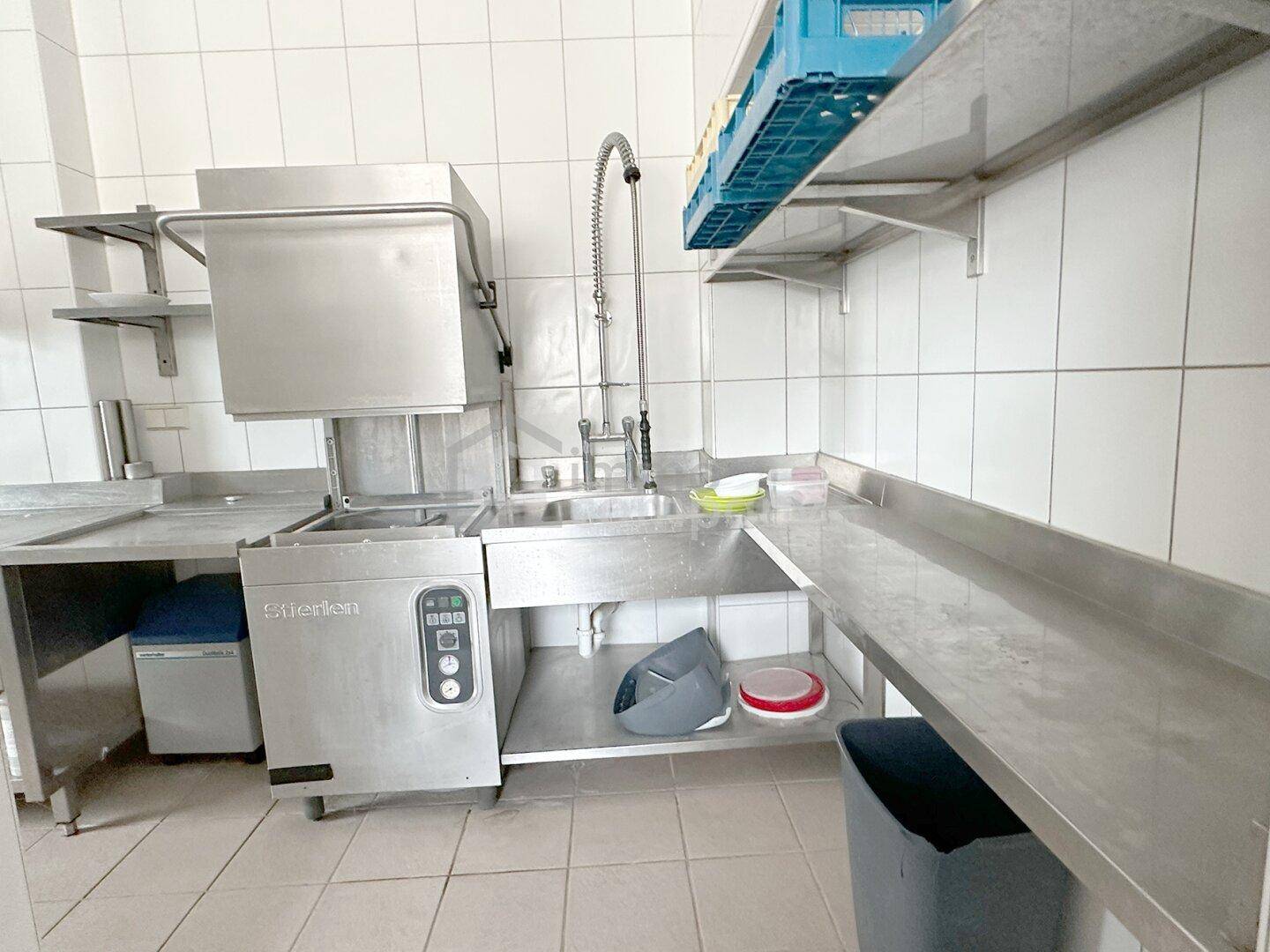 Spülbereich in einer Großküche mit professioneller Spülmaschine und Ablageflächen.
