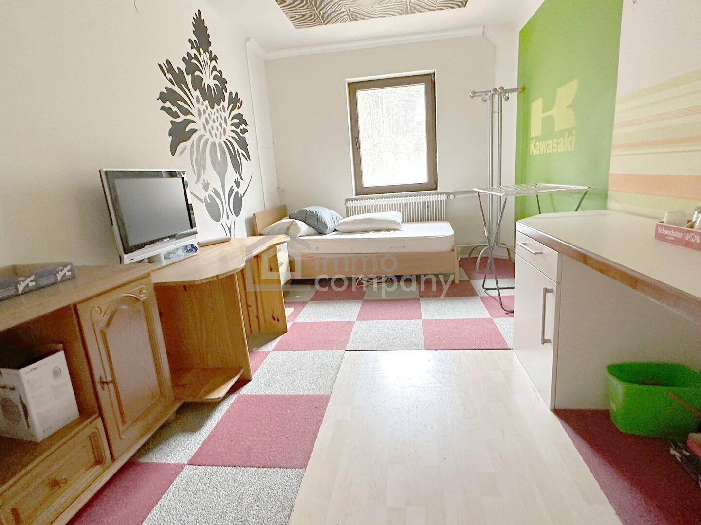 Jugendzimmer mit farbigem Teppichboden, Schreibtisch und Wanddekoration, individuell gestaltet.