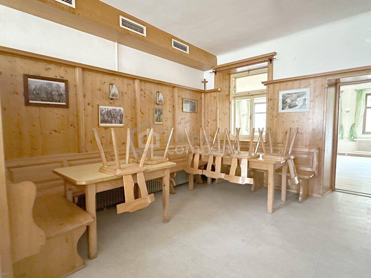 Gemütlicher Gastraum mit traditioneller Holztäfelung und aufgestellten Holztischen und Bänken.