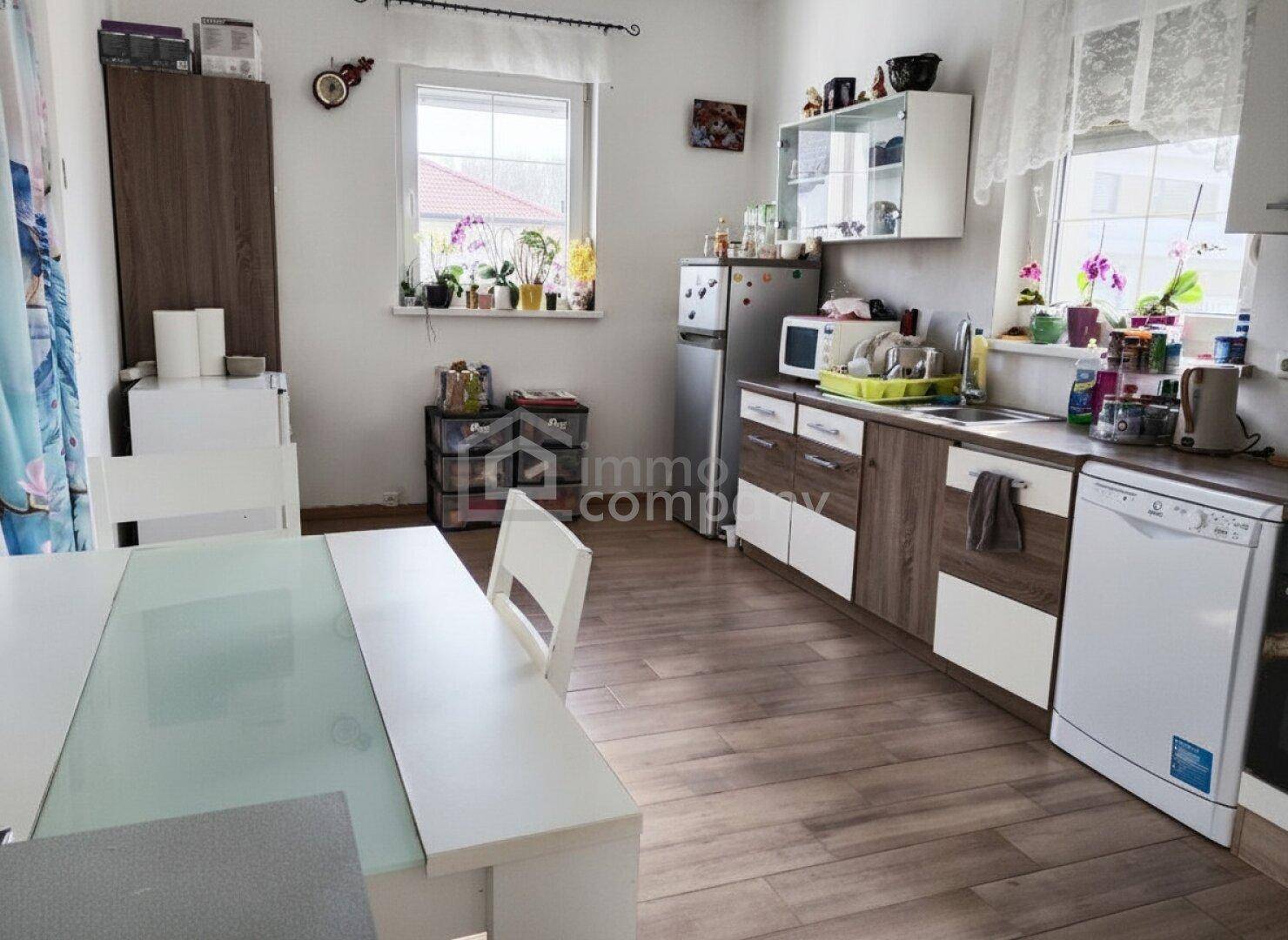 Funktionale Küche mit Holzboden, modernen Schränken und integriertem Essbereich.