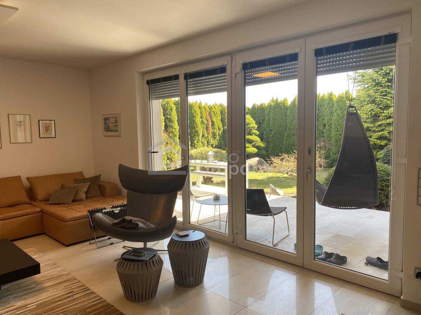 Gemütliches Wohnzimmer mit großen Fenstern, die den Blick auf den gepflegten Garten freigeben.