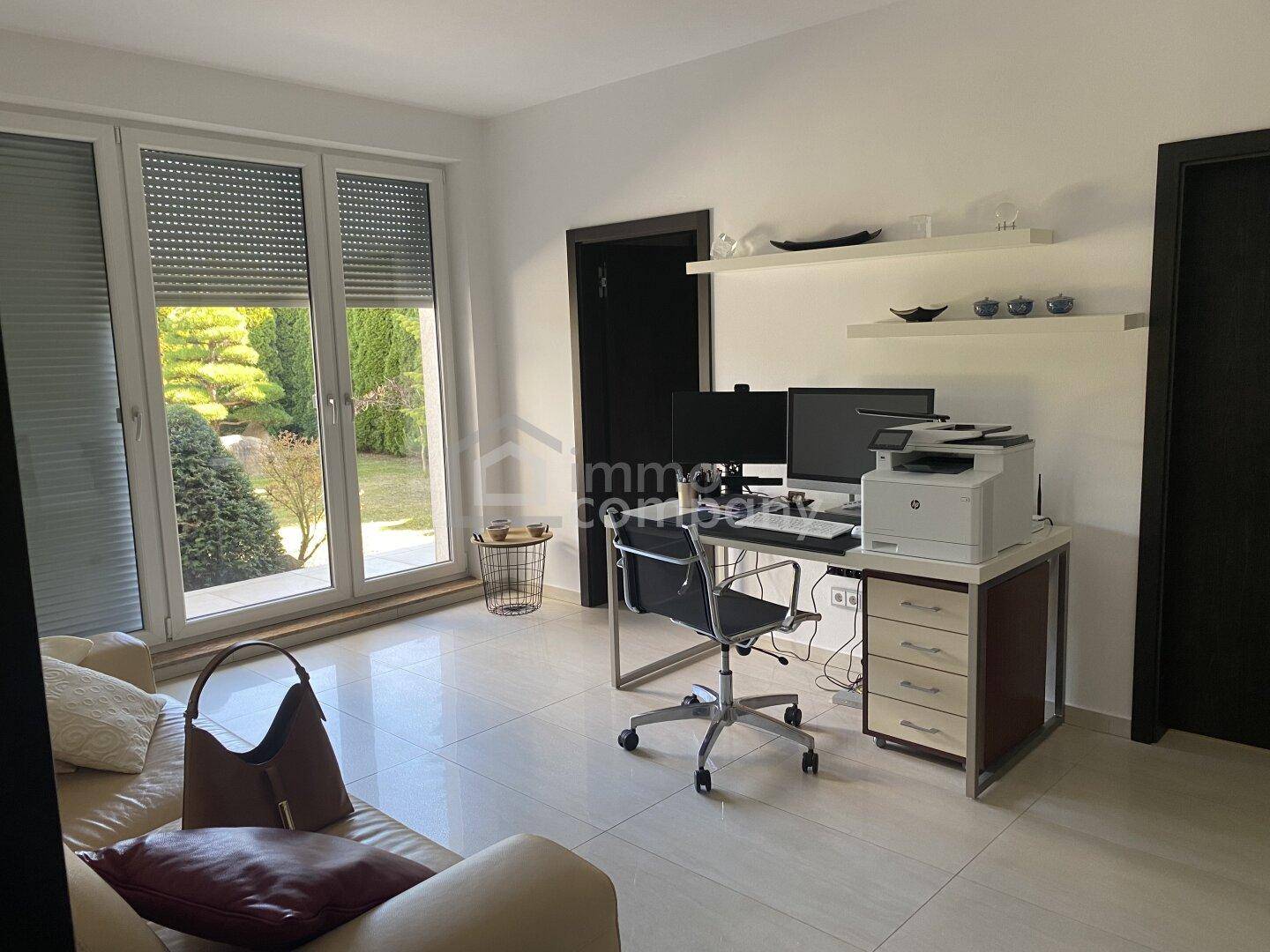 Helles Arbeitszimmer mit großen Fenstern zum Garten und funktionaler Einrichtung für Home-Office.