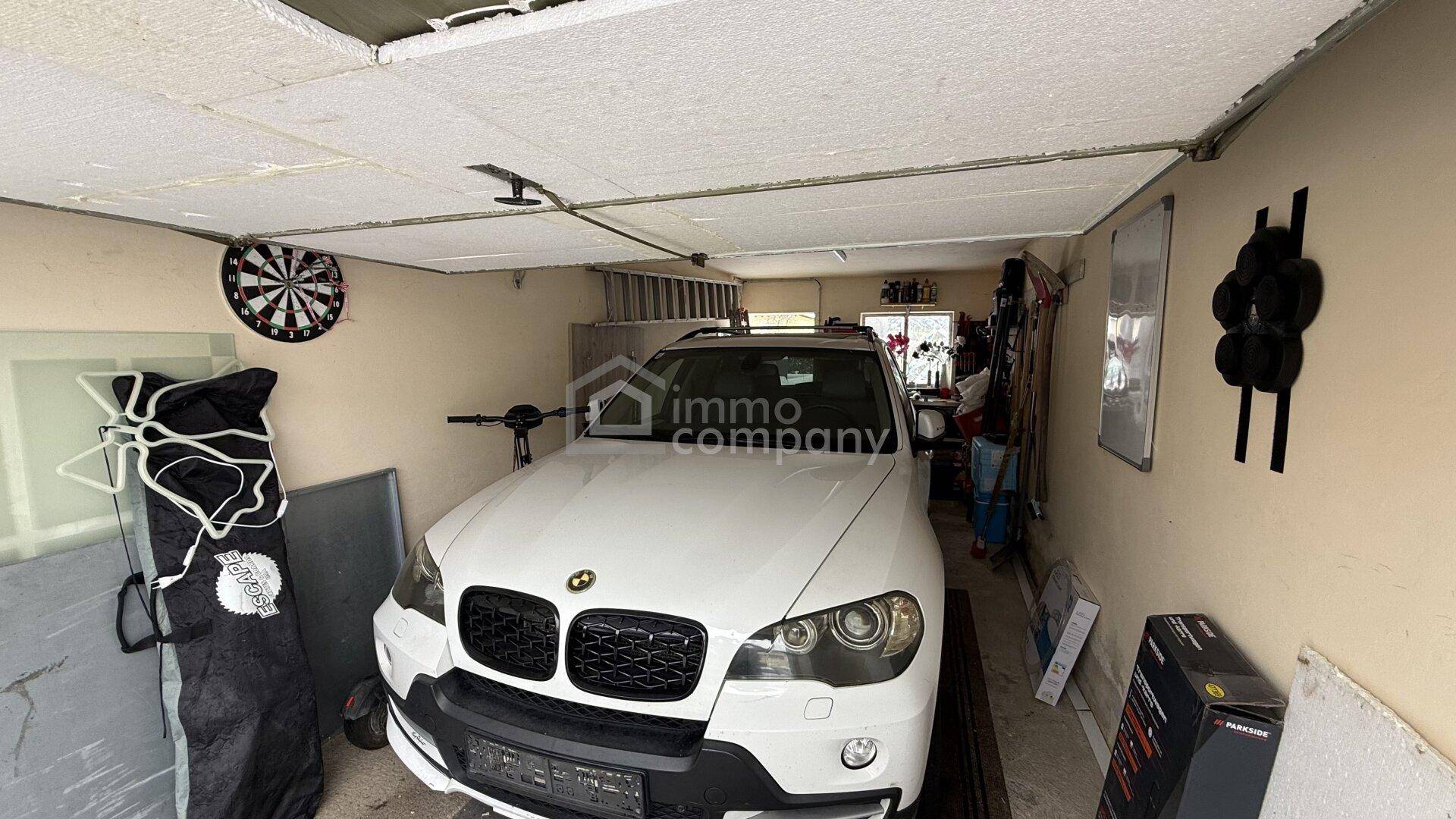 Garage mit geparktem Fahrzeug, Stauraum und Fenstern für Tageslicht.