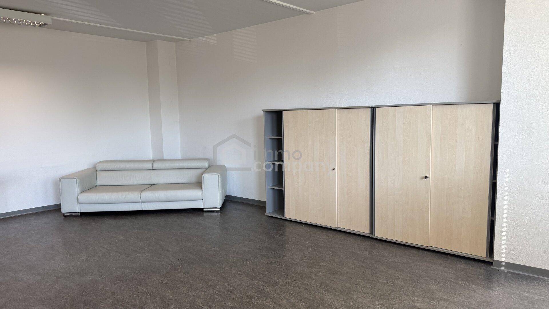 Einfacher Aufenthaltsbereich mit einem Sofa und einem großen Schrank, bereit zur individuellen Gestaltung.