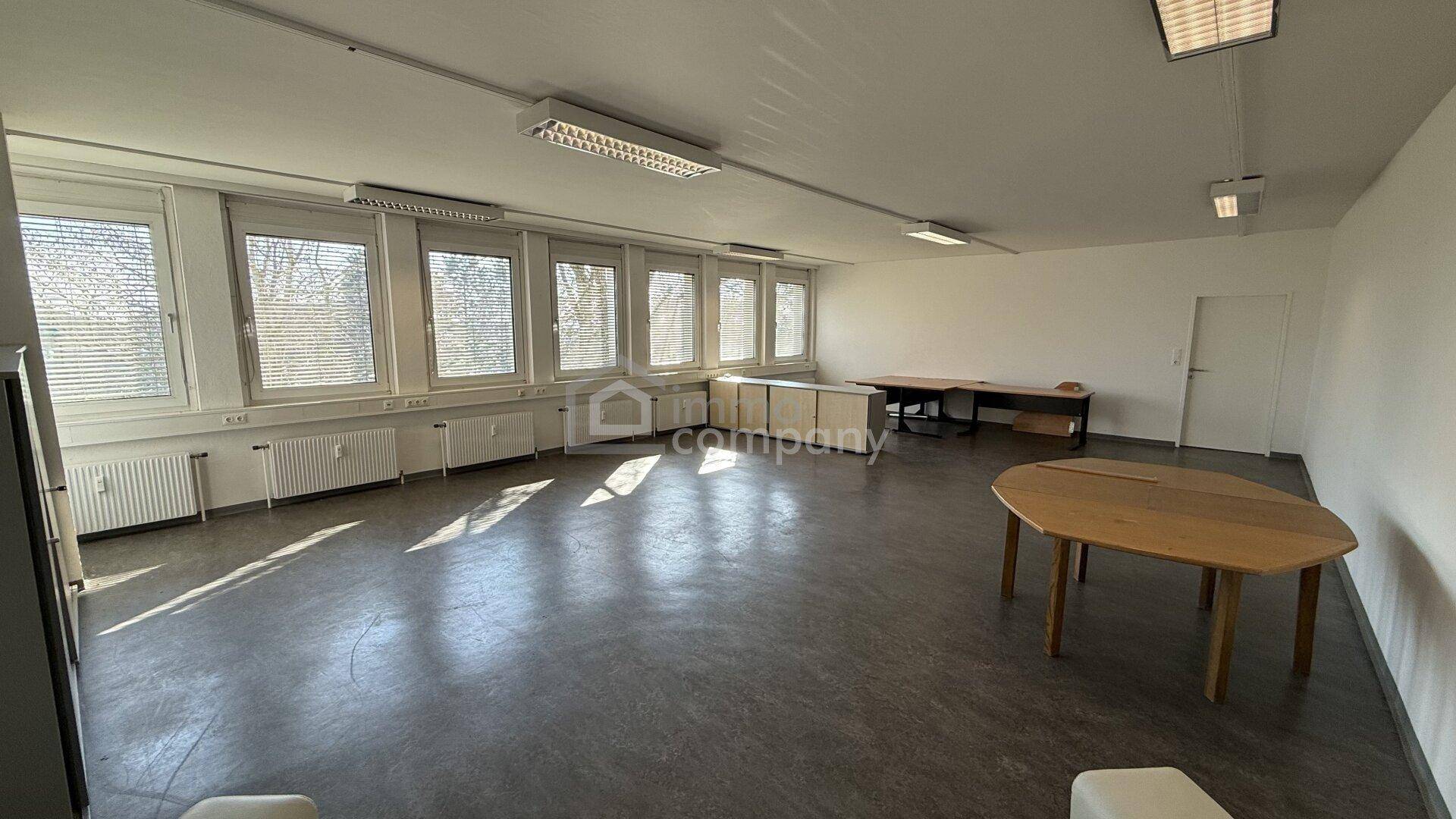 Geräumiges, leeres Büro mit vielen Fenstern und einem Besprechungstisch, ideal für flexible Nutzung.