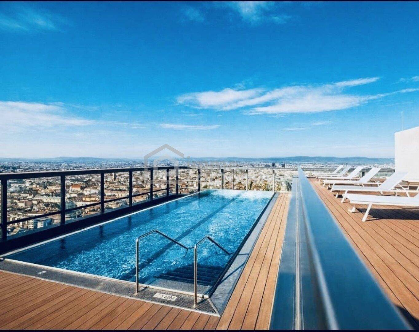 Dachterrassenpool mit atemberaubendem Stadtblick und Liegebereich unter blauem Himmel.