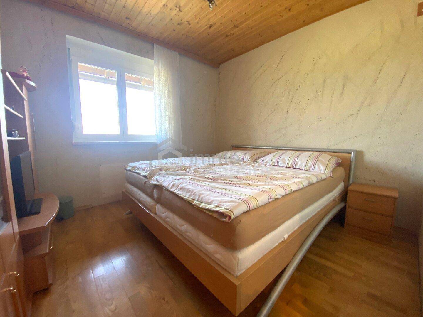 Schlafzimmer mit Doppelbett, Holzdecke und Laminatboden, hell und geräumig.