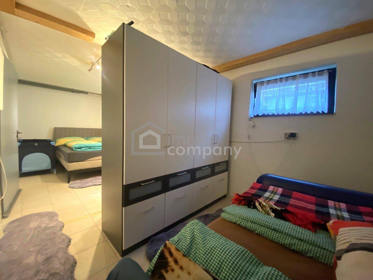 Ausgebauter Kellerraum mit Bett und Kleiderschrank, nutzbar als Gäste- oder Hobbyzimmer.