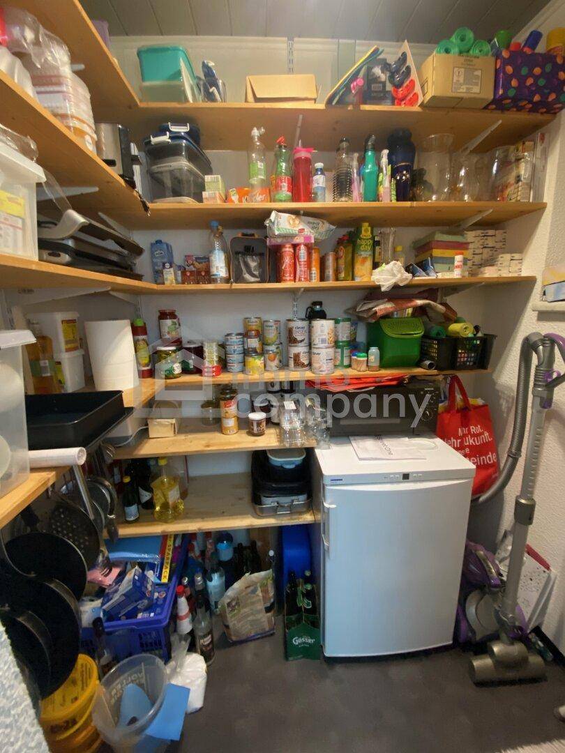 Praktischer Hauswirtschaftsraum mit vielen Regalen für Vorräte und einem kleinen Kühlschrank.