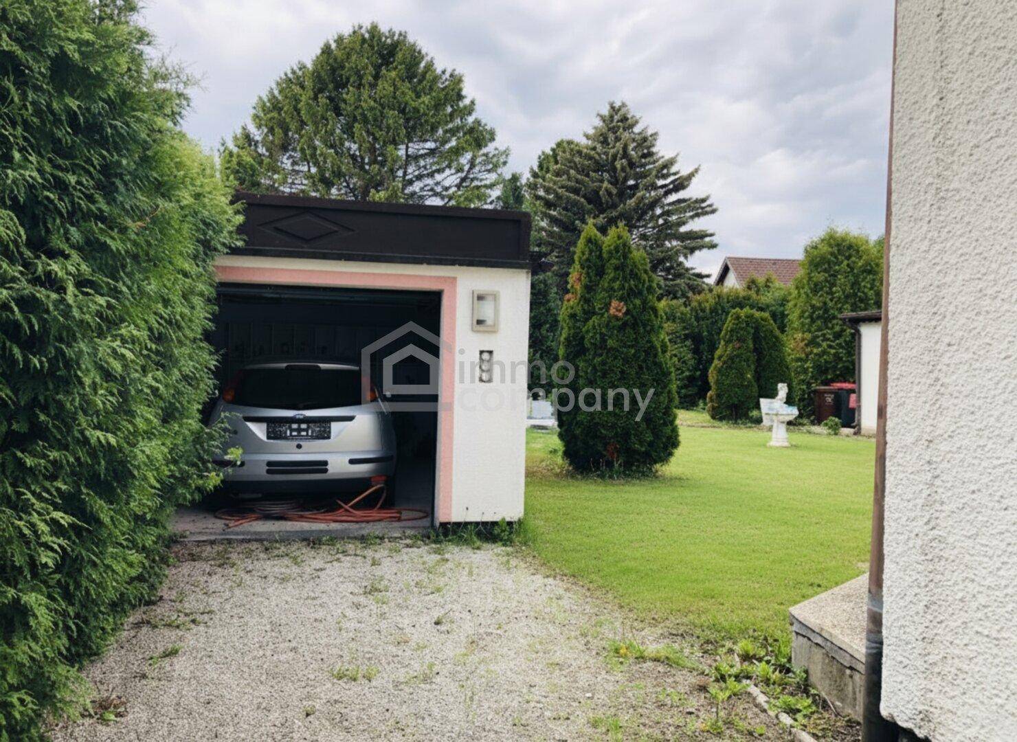 Einzelgarage mit einem geparkten Auto und Zugang zum Gartenbereich.