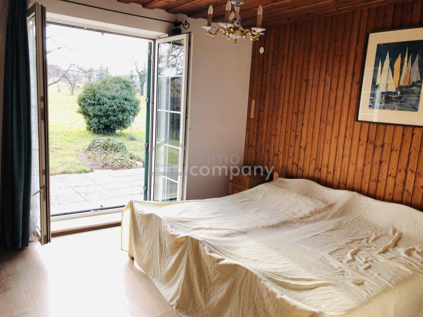 Schlafzimmer mit Holzwänden, Holzboden und direktem Zugang zum Garten.