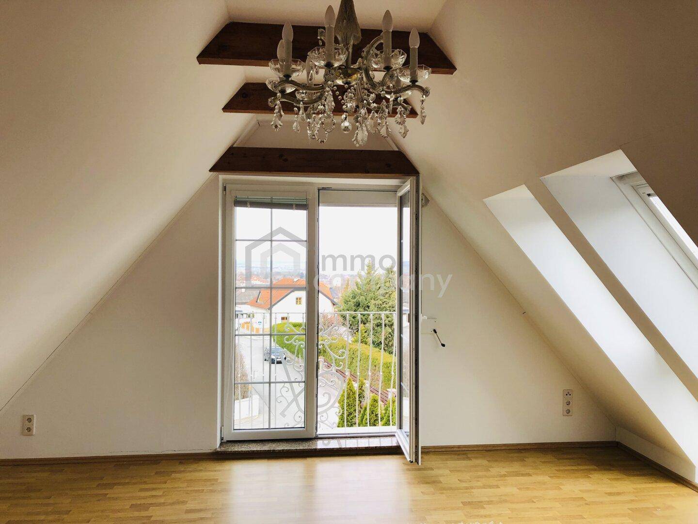 Helles Dachgeschosszimmer mit Holzboden, Dachschrägen und Blick ins Freie.